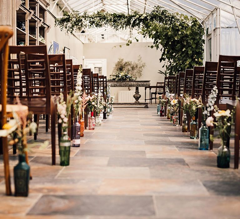 Greenhouse conservatory style ceremony room with glass bottle aisle decoration at Houghton Lodge