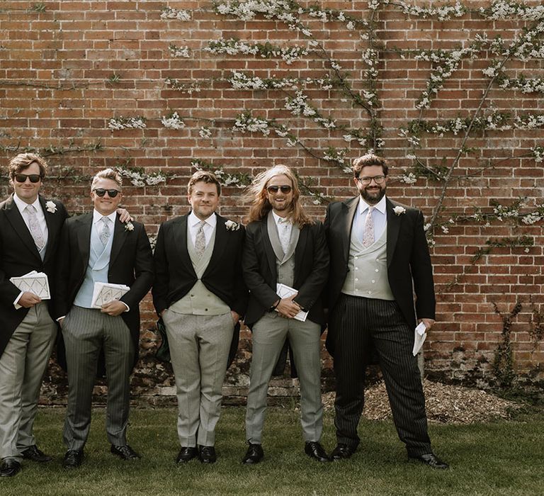 Groom and groomsmen in black morning suit jackets with different colour and style waistcoats and trousers 