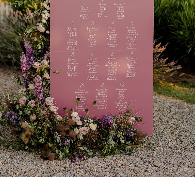 Purple table plan outdoors surrounded by florals in Tuscany 