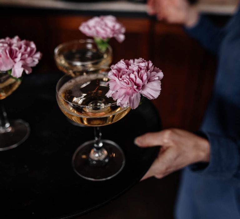 champagne served in coupe glasses with pink carnation flowers 