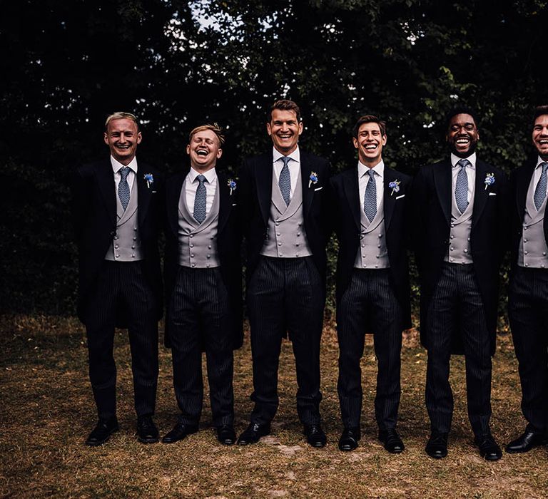 Groom with the groomsmen in matching morning suits with striped trousers, grey waistcoats and blue ties and buttonholes 