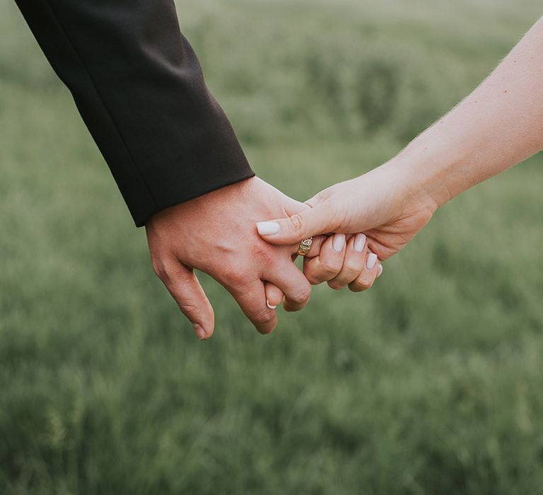 Bride with pale neutral wedding nails holding hands with the groom 