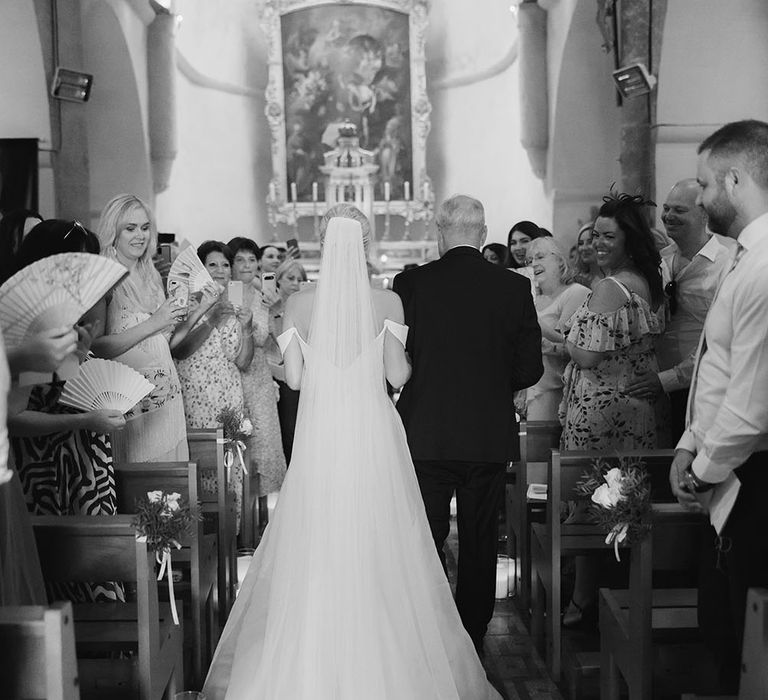 Bride walks down the aisle in church wedding floor-length veil in the South of France 