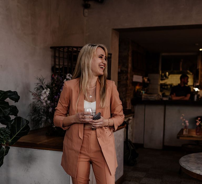 Bridesmaid wears orange bridesmaid suit complete with white T-shirt for modern styled wedding 