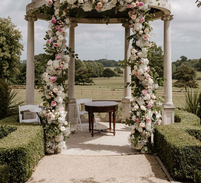 Outdoor wedding dome finished with pastel pink and white florals with green foliage