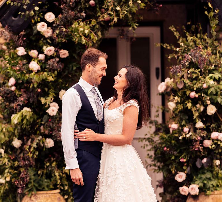 Bride and groom stand in front of the bride's family home for their stay at home wedding 