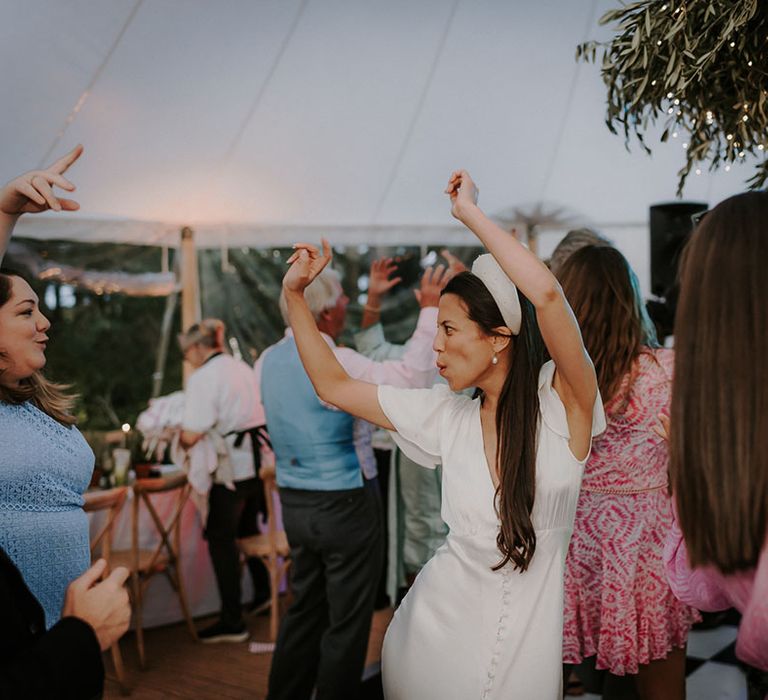 Bride in a white satin button Ghost wedding dress dancing with her guests on the dance floor 