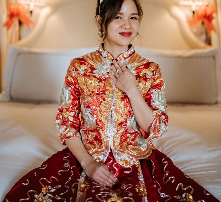 Bride wears traditional Chinese wedding dress with red and gold embellishment and gold bridal crown