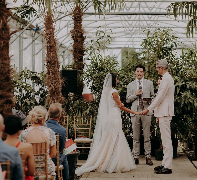 Bride and Groom hold hands during wedding ceremony at Architectural Plants Venue