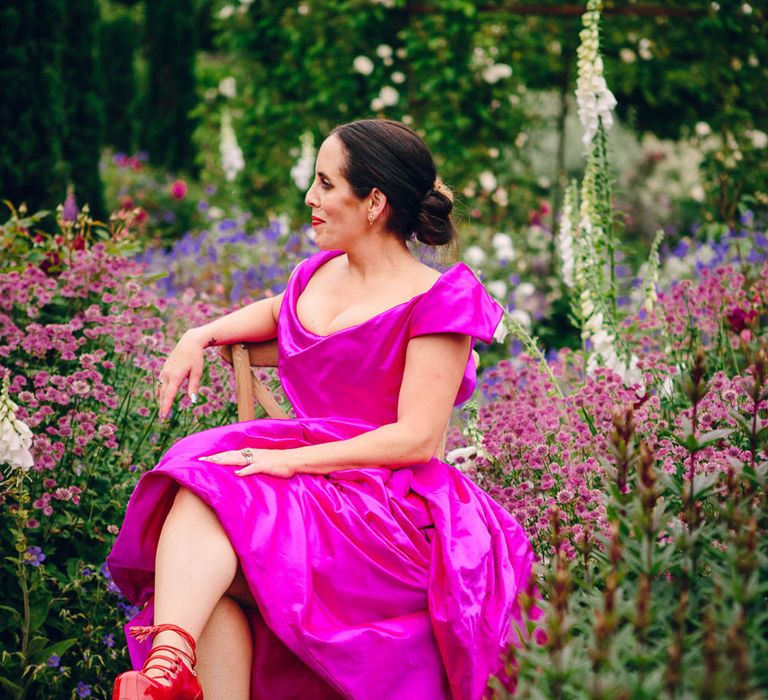 Bride in off the shoulder front ruching pink Vivienne Westwood wedding dress and Vivienne Westwood elevated red patent leather platform heels with shoe-string fastening  