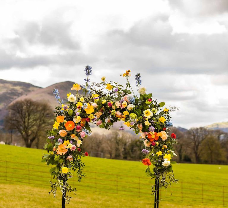 Colourful Spring floral arch for outdoor wedding ceremony at Plas Dinam 