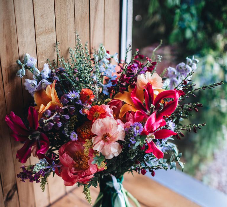 Bright purple, orange, and pink wedding bouquet with lilies, wax flower, and more 