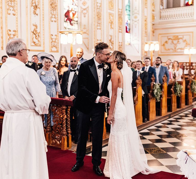 The bride and groom share their first kiss as a married couple in the luxury Witley Court Church