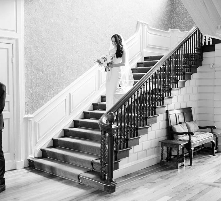 Bride in a Kelly Faetanini walking down the stairs to greet her husband in a navy suit for their 'first look' 