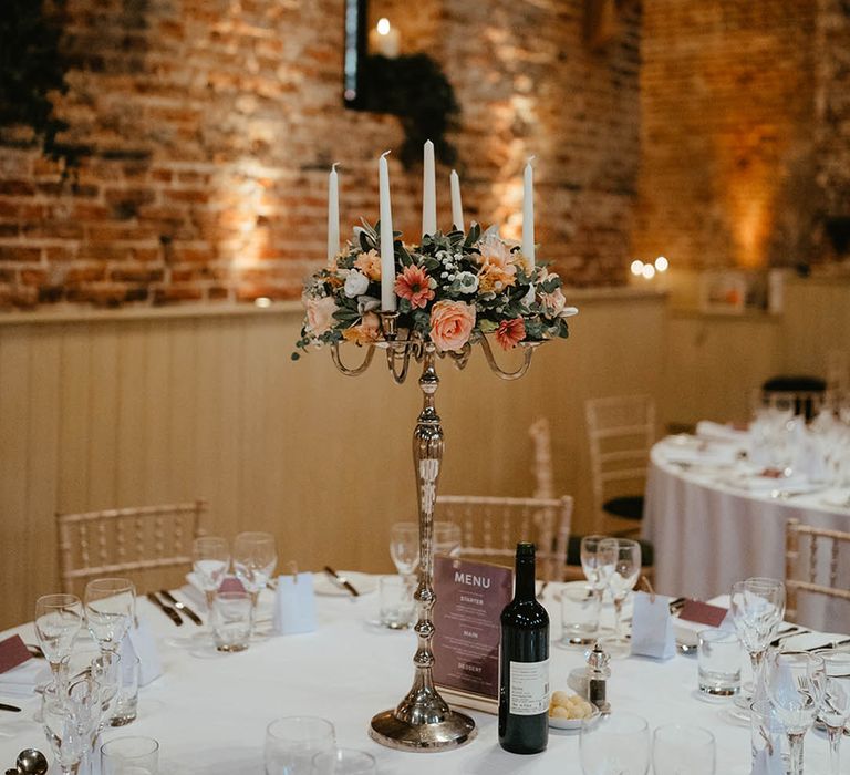 Orange and peach floral tall gold candelabra centrepiece decoration with white candles for classic style rustic barn wedding 