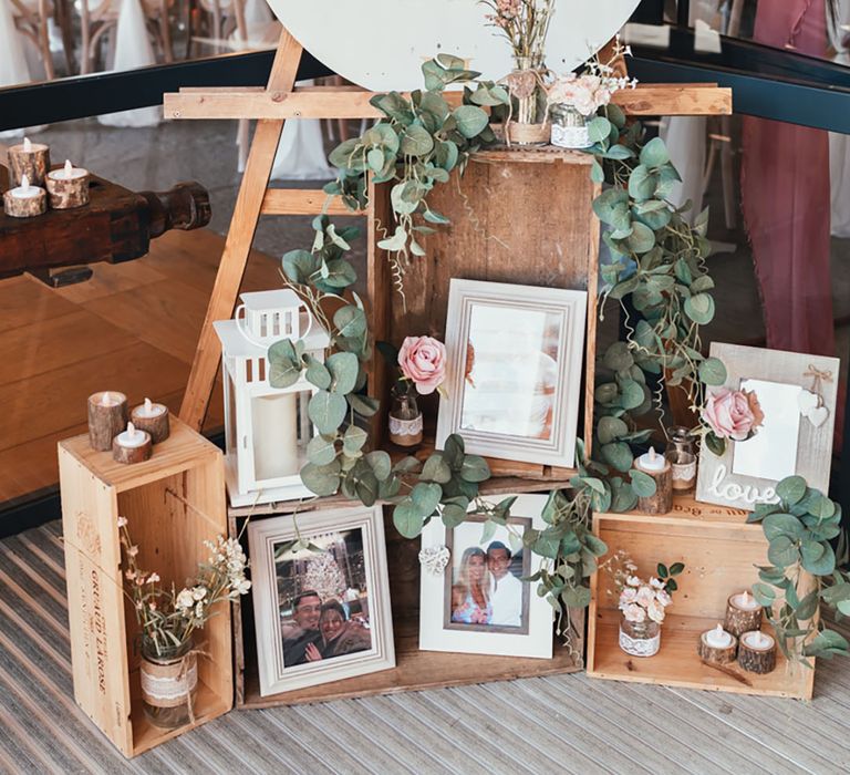 White and gold clock order of the day wedding signage with moveable arms surrounded by wooden crates and family photos 