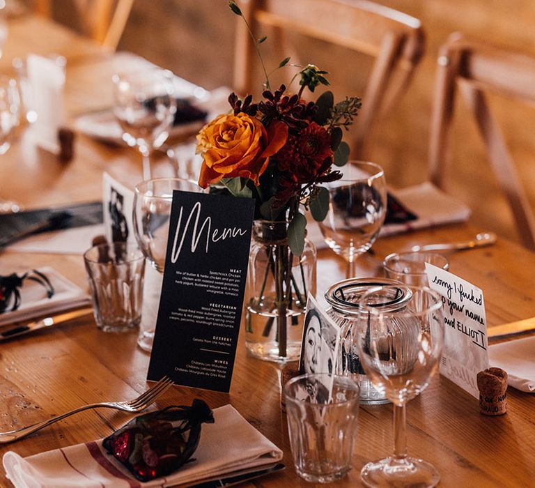 Black and white wedding menu resting on the autumnal and rustic wedding tables for the wedding breakfast 