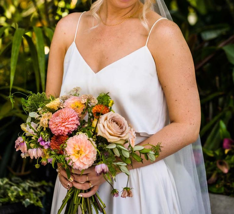 Bride wearing Catherine Deane bridal separates with bright bridal bouquet with cathedral length veil with ruffle detail 