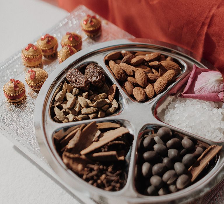 Traditional Indian wedding snacks on clear tray with burnt orange fabric 