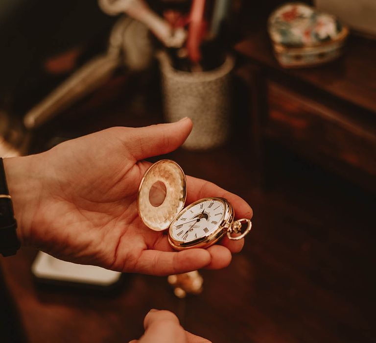 Groom holding gold pocket watch groom's accessory 