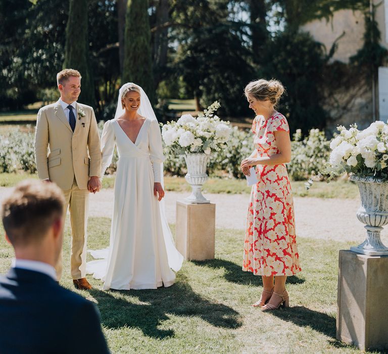 Outdoor wedding ceremony at Château de Malliac with bride in a bespoke Emma Beaumont wedding dress and groom in a beige suit