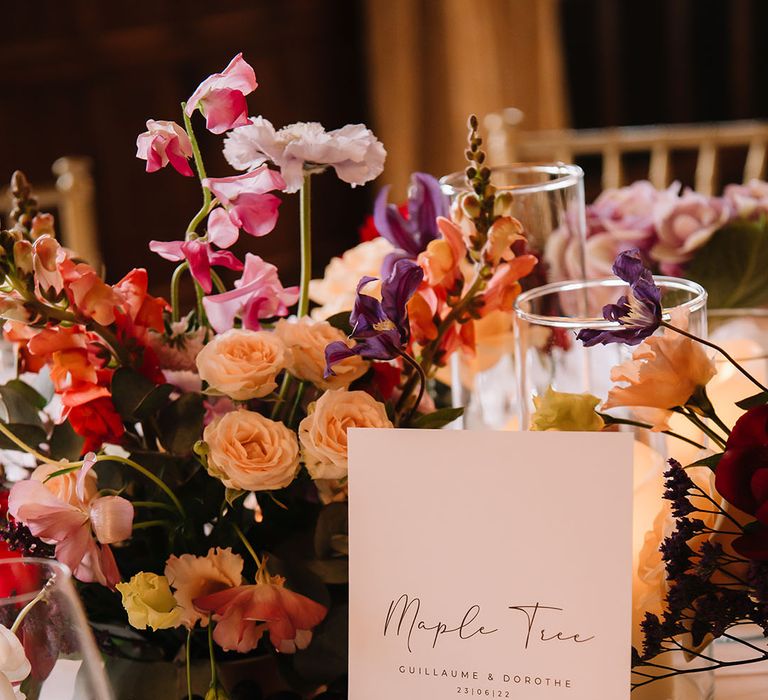 Bright and vibrant flower arrangement on the table with large wedding table name sign 