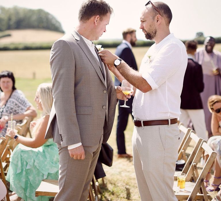 Best man in white shirt helps the groom with a last minute fix at the altar 