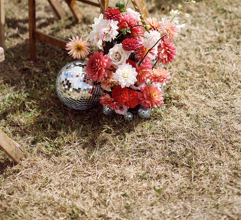 Red, pink, and white wedding flowers with dahlias and roses with disco balls 