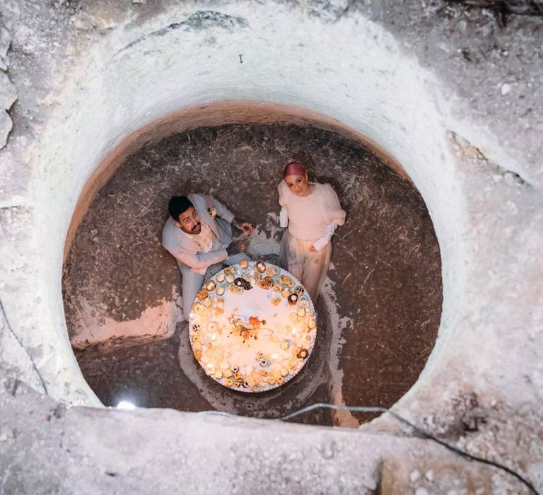 Bride and groom sitting at wedding grazing table through one of the Margate Caves