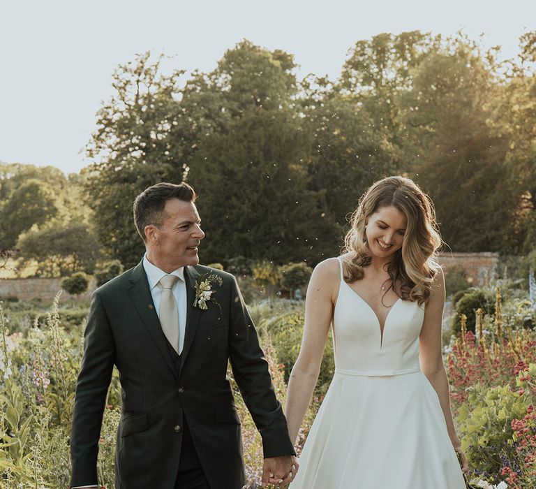 The bride and groom walking through the gardens at Kelmarsh Hall together 