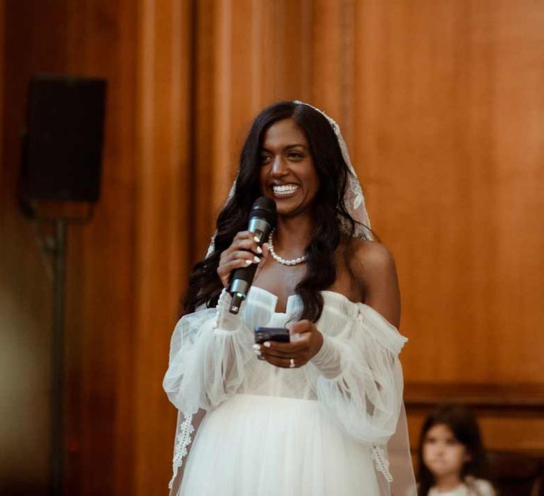 Bride in off the shoulder layered tulle wedding dress doing bridal speech at Inner Temple Hall vow renewal 