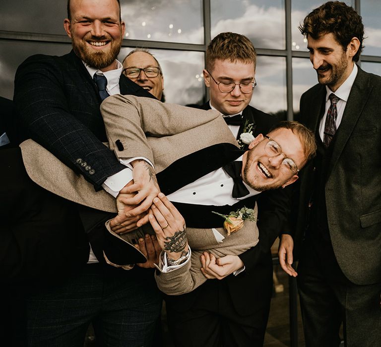 The groom and groomsmen pose together for funny wedding photo at Botley Hill Barn in Surrey 