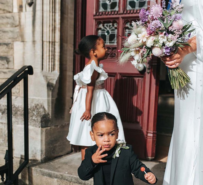 Page boy in black suit and shirt with white flower buttonhole at registry office wedding 