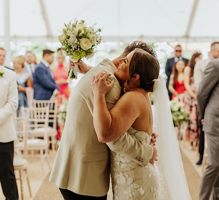 The bride and groom hug at their wedding ceremony at Houchins wedding venue 