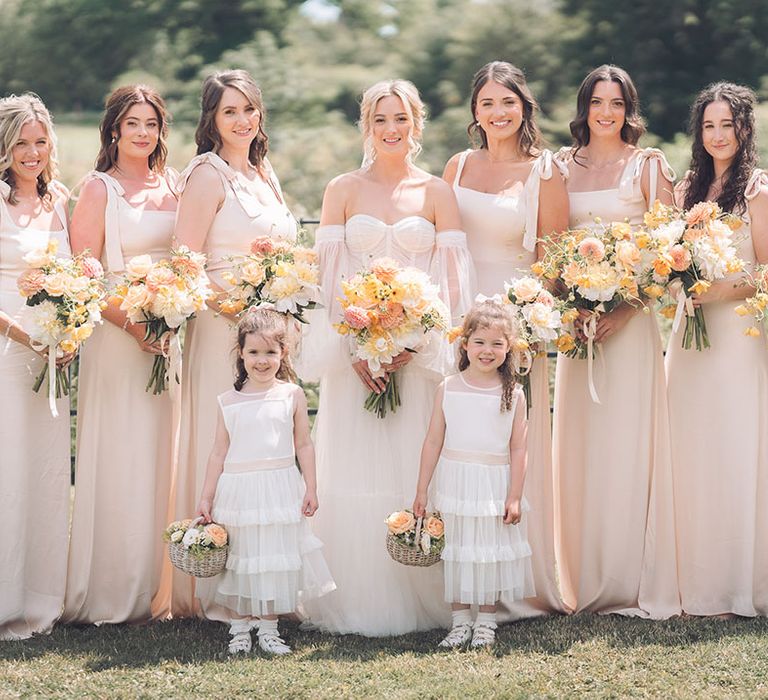 Bridal party photography with pale peach bridesmaid dresses and yellow wedding flowers