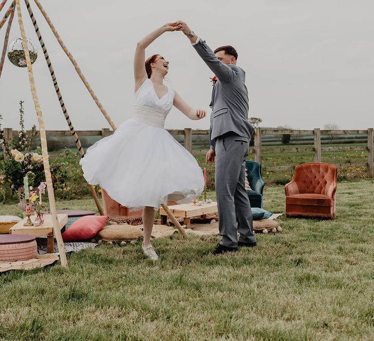 Groom in grey suit spinning bride around in short knee length wedding dress 