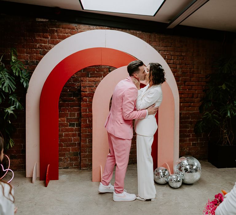 The bride and groom share their first kiss as a married couple at The Shack Revolution with pink arches as altar decor