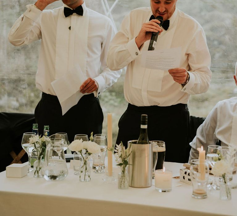 The two best men in white shirts and black bow ties read out their wedding speeches 