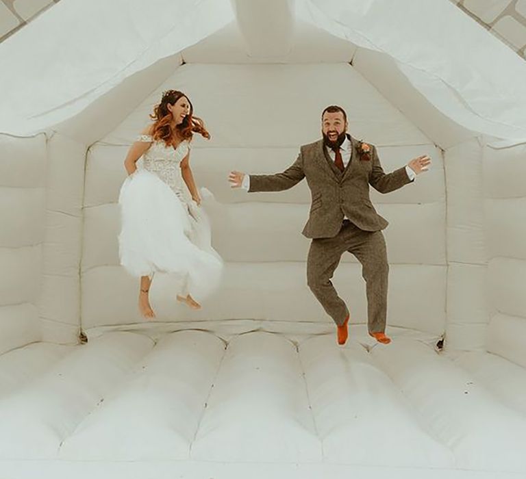 Bride and groom jumping on bouncy castle for fun wedding entertainment