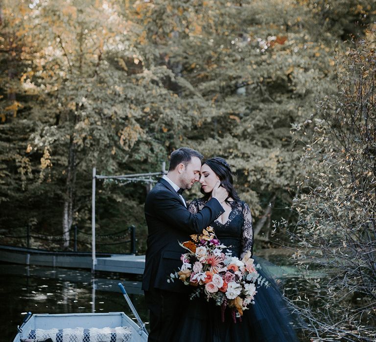 Bride holding pink and yellow autumnal wedding bouquet posing with the groom for couple portraits