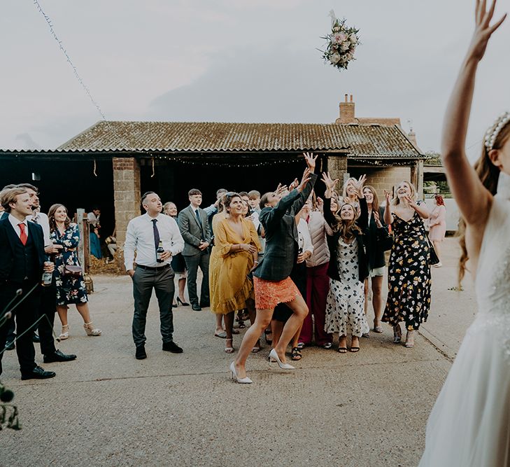 Bride in Inbal Dror wedding dress throwing her bouquet 