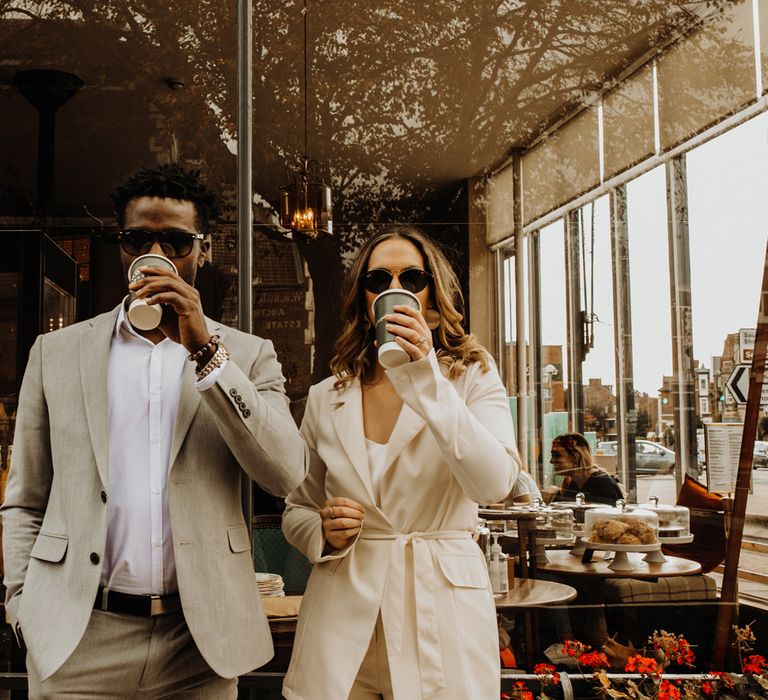 Bride and groom in sunglasses enjoying a coffee at city elopement 