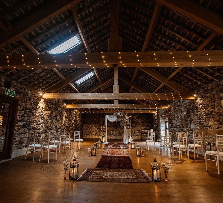 Boho wedding aisle with rugs lanterns and fairy lights