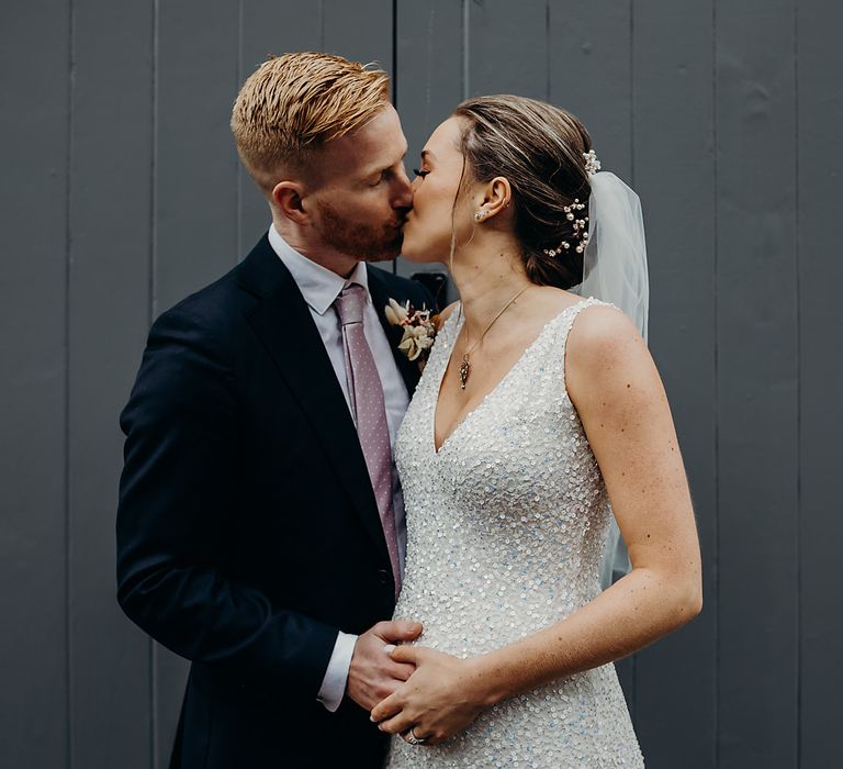 Groom kissing his pregnant bride in a sparkly wedding dress