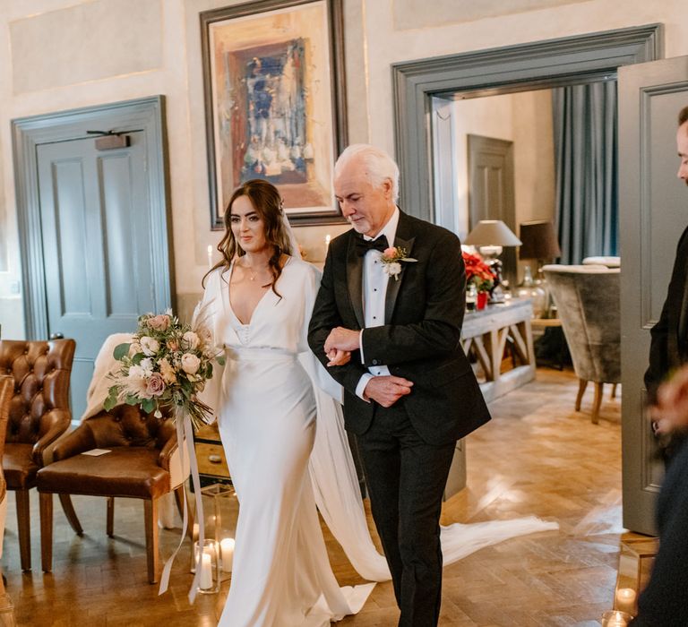 Father of the bride walking his daughter down the aisle, with neon sign, pampas grass and rose bouquet and smiling wedding guests