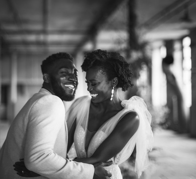 Black and white portrait of bride and groom laughing at their luxury industrial wedding 