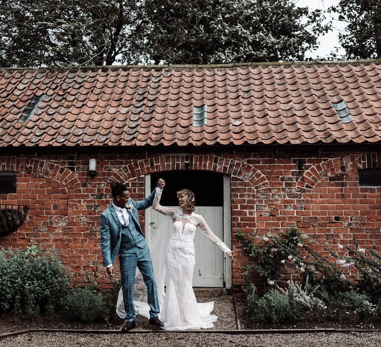 The bride and groom dancing outside the barn, the bride wears a detachable cape