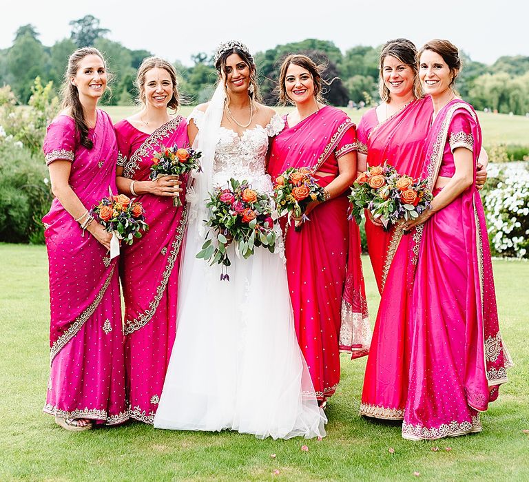 Bride and bridesmaids in hot pink dresses holding colourful bouquets 