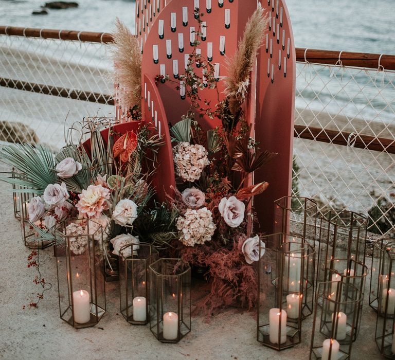 Dusky pink geometric escort card display decorated with lanterns and dried flower arrangements 