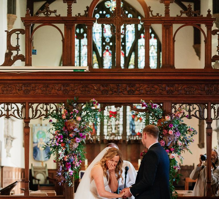 Blonde haired bride and groom laugh at the altar during ceremony